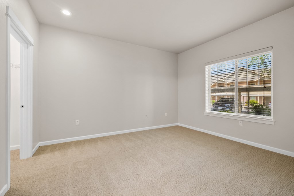 an empty living room with a window and carpet