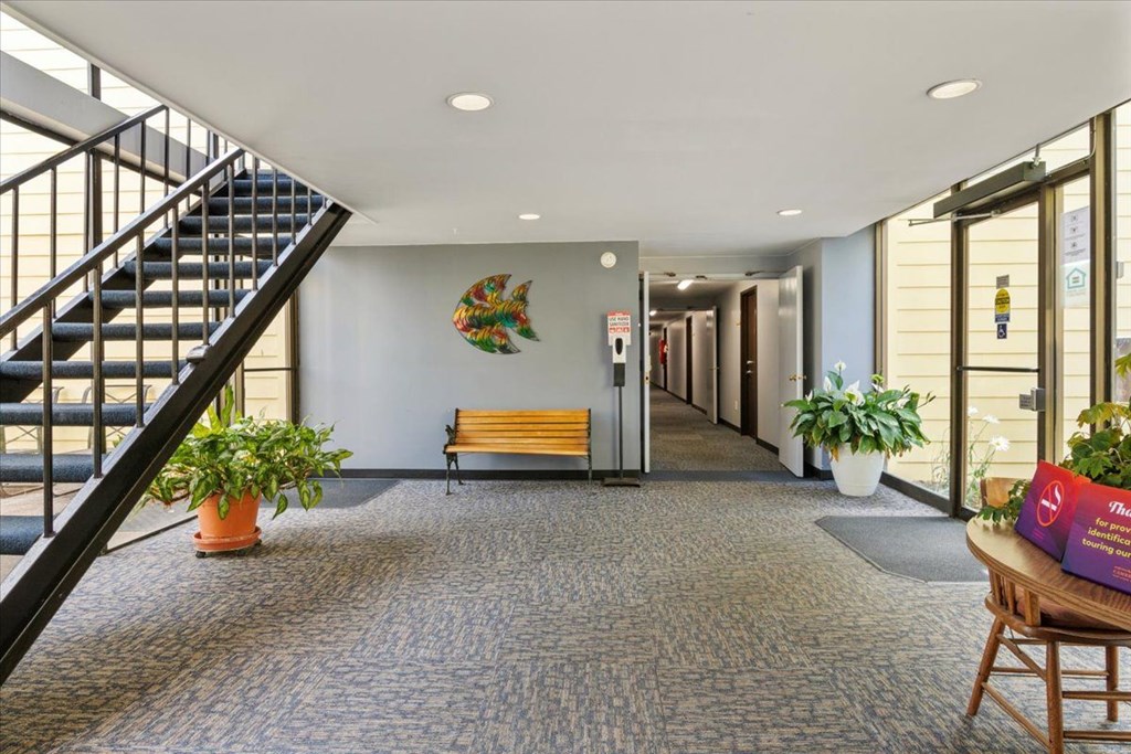 A hallway with a staircase on the left and a bench in the middle.