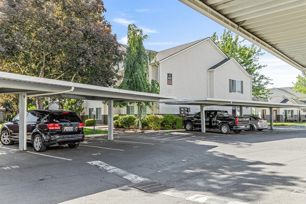 A parking lot with two cars parked under a covered area.