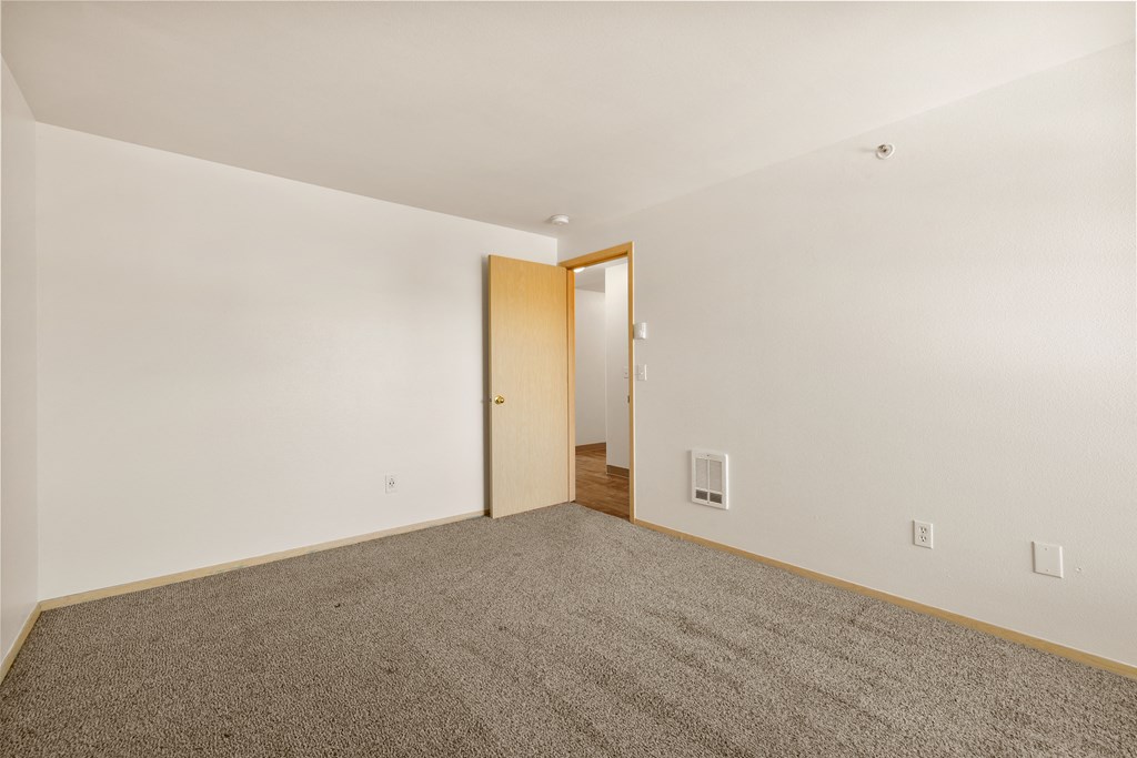 a living room with carpet and a door to a hallway