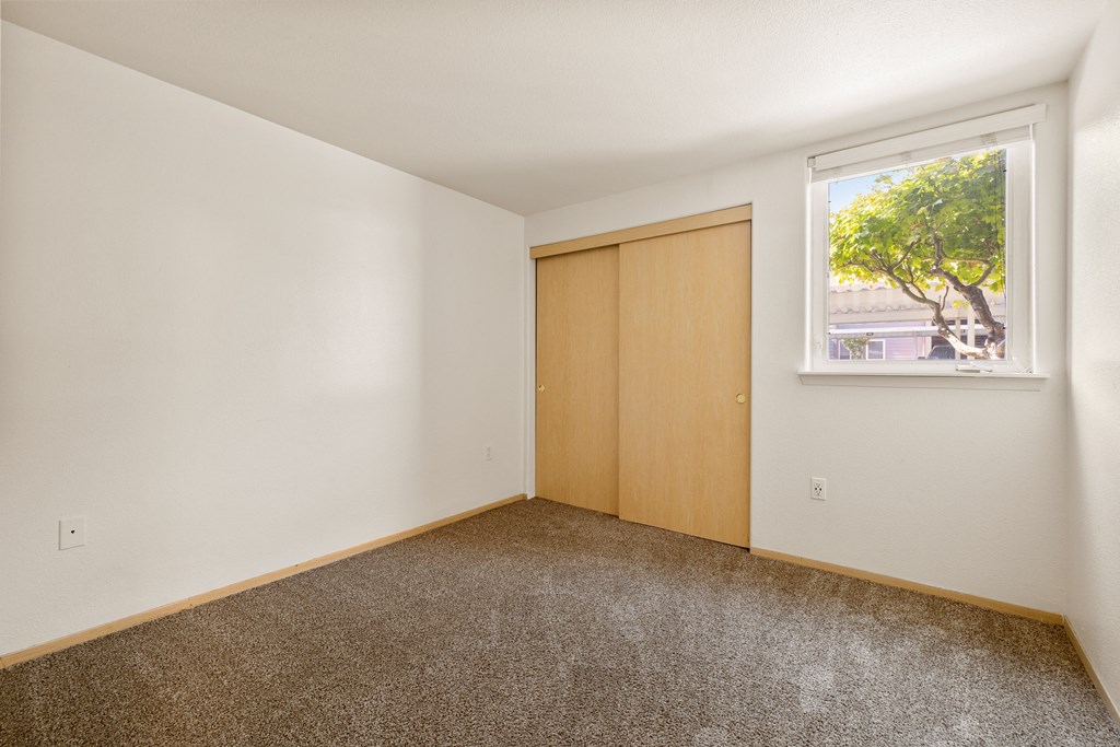 an empty room with a window and a door to a closet