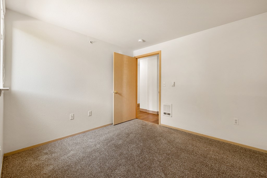 a living room with carpet and a door to a hallway