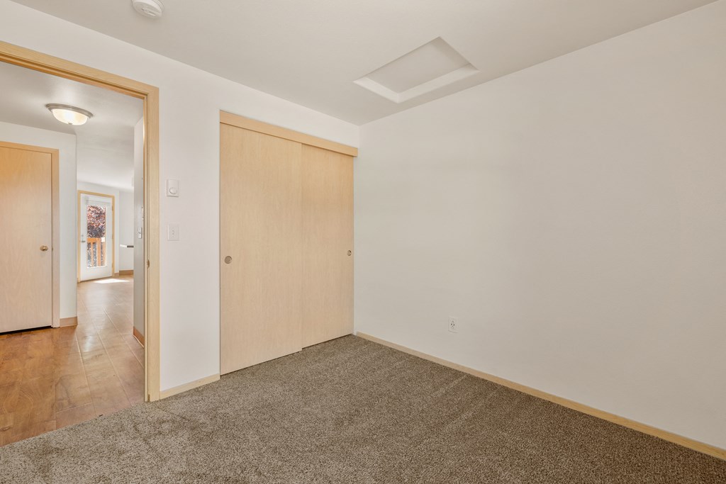 a living room with a door to a hallway and a carpeted floor