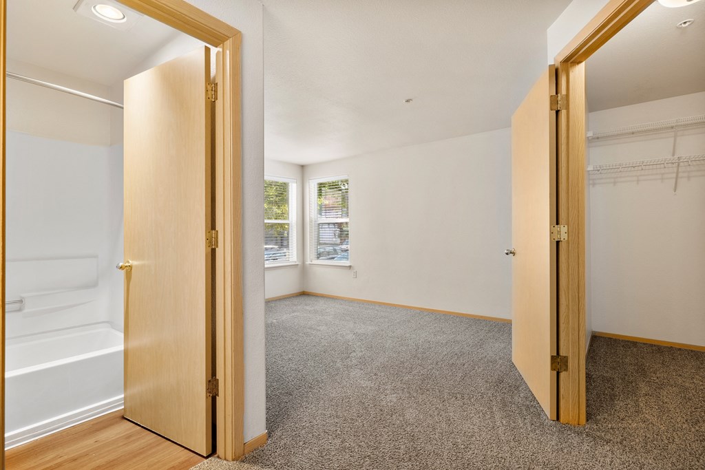 an empty bedroom with a door open to a bathroom