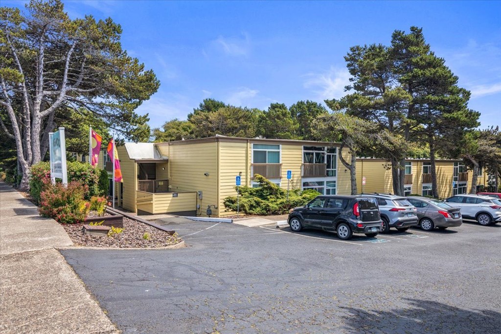 A parking lot with cars and a building with flags in front.