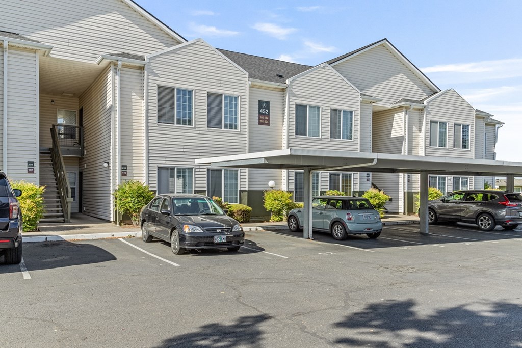 A parking lot in front of a building with cars parked.