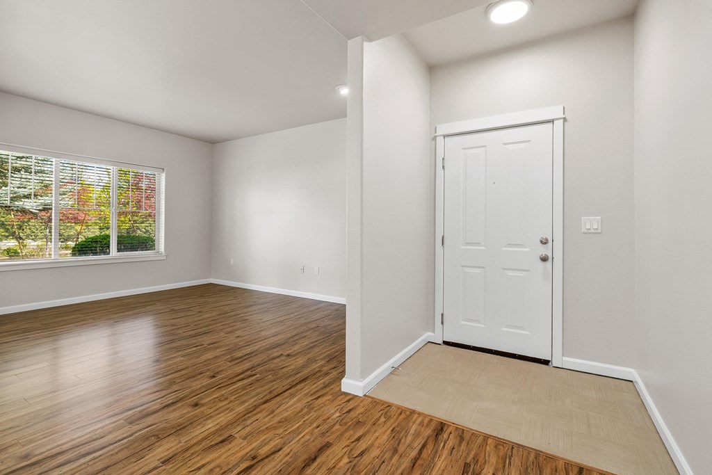 an empty living room with a white door and a window