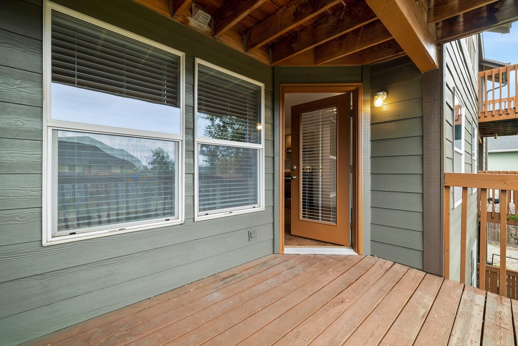 the front porch of a green house with a wooden deck