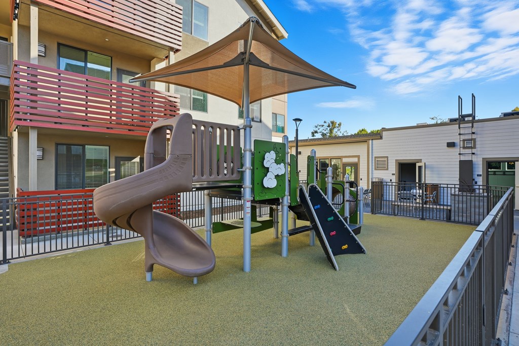 A playground with a slide, a climbing frame and a swing.