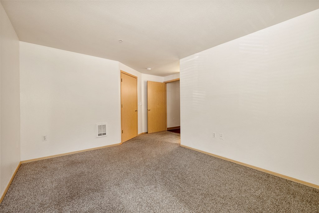 a spacious living room with carpet and white walls