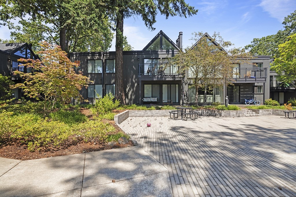 A modern building with a black exterior and a large courtyard with a picnic table.