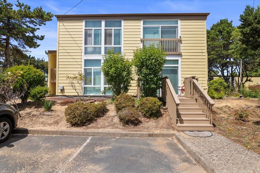 A two-story house with a beige exterior and a brown staircase leading to the front door.