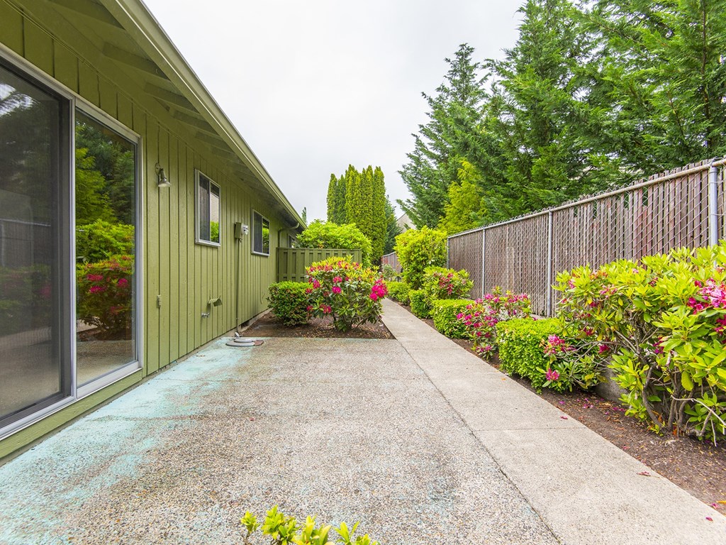 a walkway in front of a green house with colorful flowers
