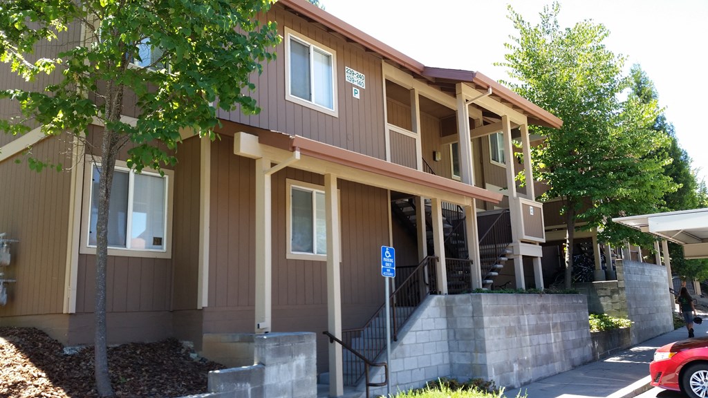 a brown building with stairs and trees in front of it