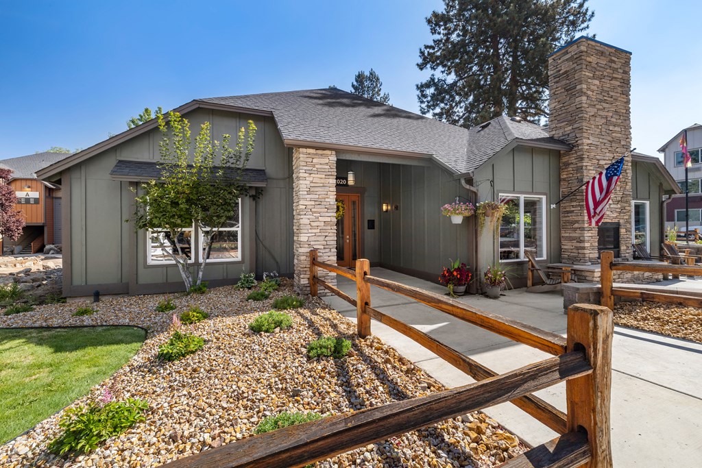 the front of a house with a yard and a wooden fence