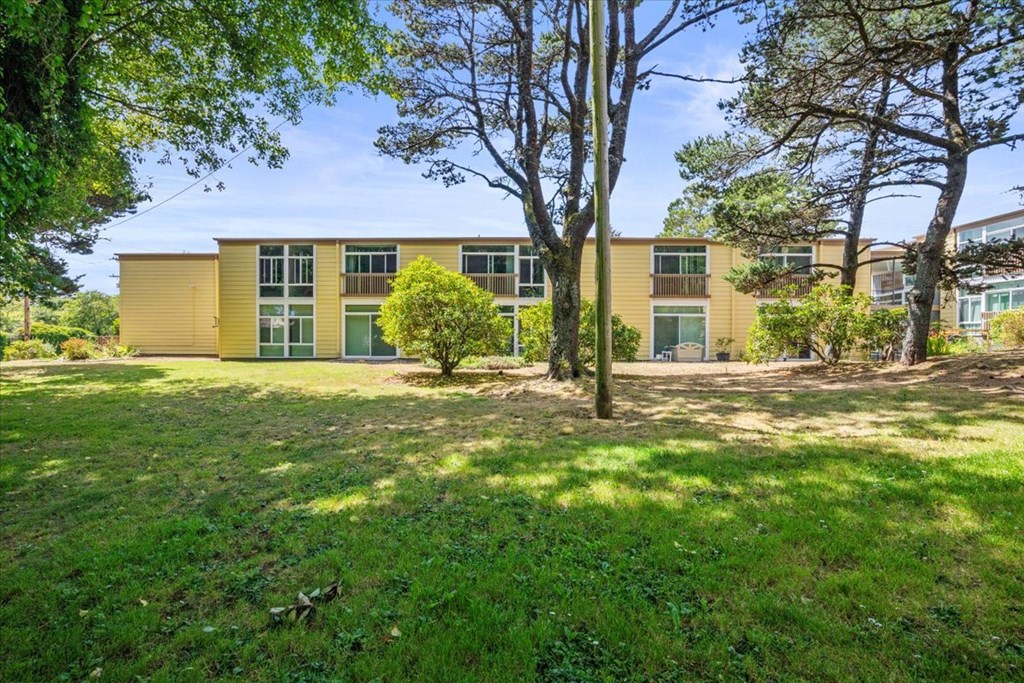 A yellow building with a green lawn in front.
