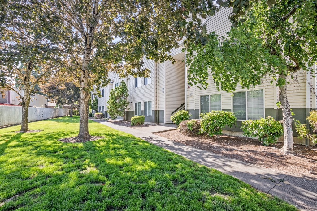 A tree in front of a building with a green lawn.