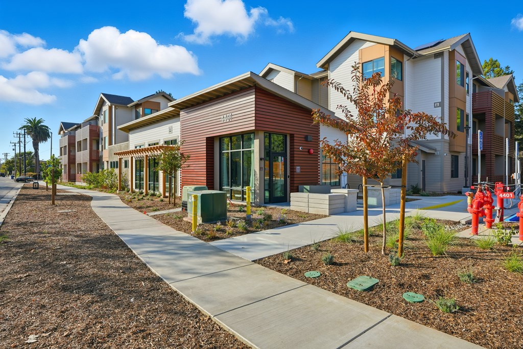 A row of modern houses with a sidewalk in front.