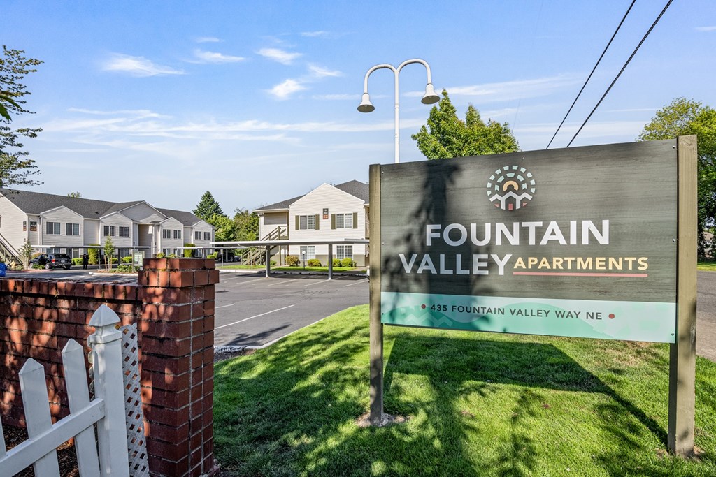 A sign for Fountain Valley Apartments stands in front of a row of houses.