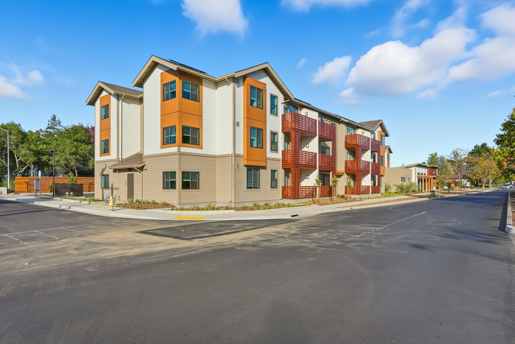 A large apartment complex with a parking lot in front.