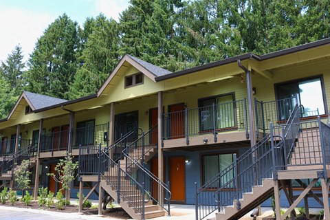 A yellow building with a balcony and stairs leading to the second floor.
