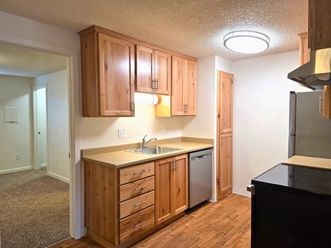 A kitchen with wooden cabinets and a black counter.
