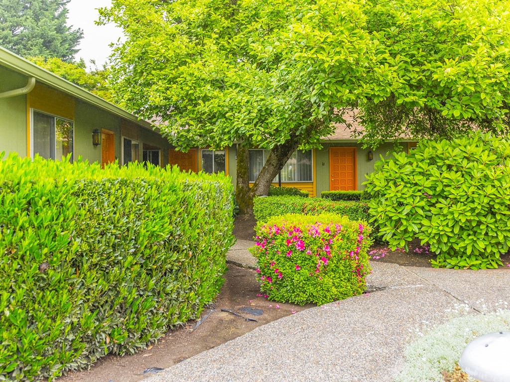 a house with hedges and flowers in front of it