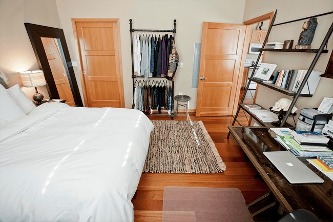 a bedroom with a white bed and a closet with clothes on it