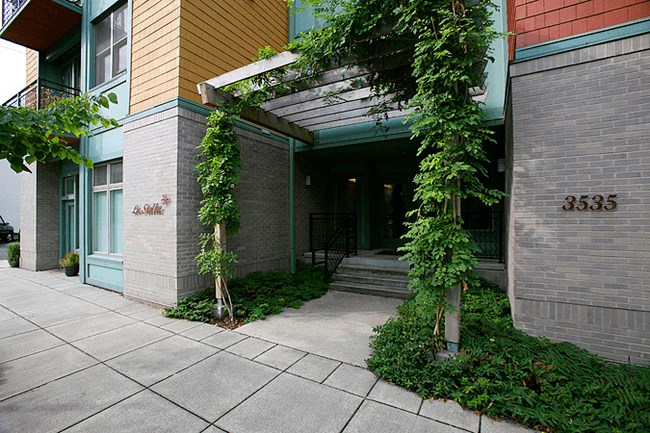 the front of a building with a porch and plants
