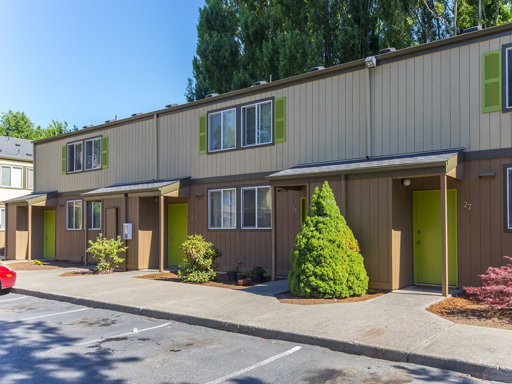 a brown building with green doors and windows and a parking lot