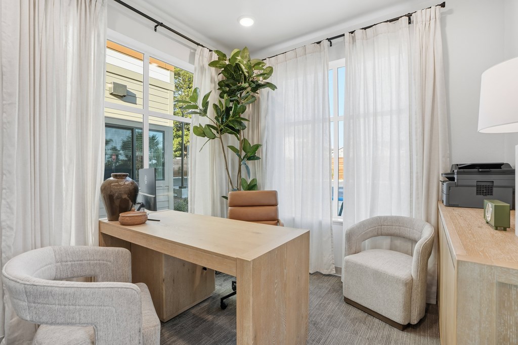 A room with a desk, chairs, and a plant.