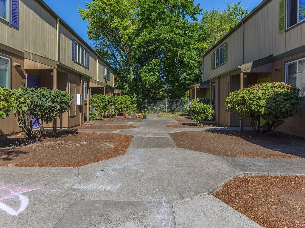 a pathway between two apartment buildings with graffiti on the ground