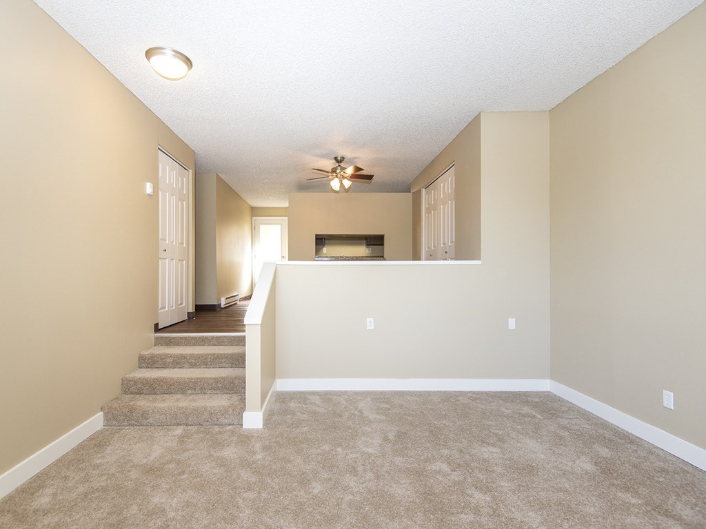 an empty living room with carpet and a ceiling fan
