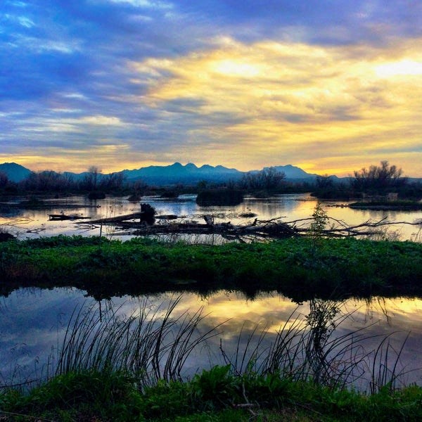a sunset over a body of water with mountains in the background
