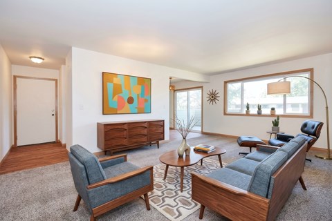 A living room with a blue couch, a chair, a coffee table, and a painting on the wall.