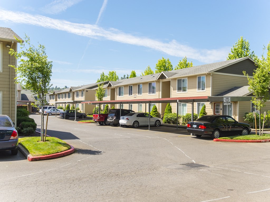 a parking lot with cars parked in front of a row of buildings