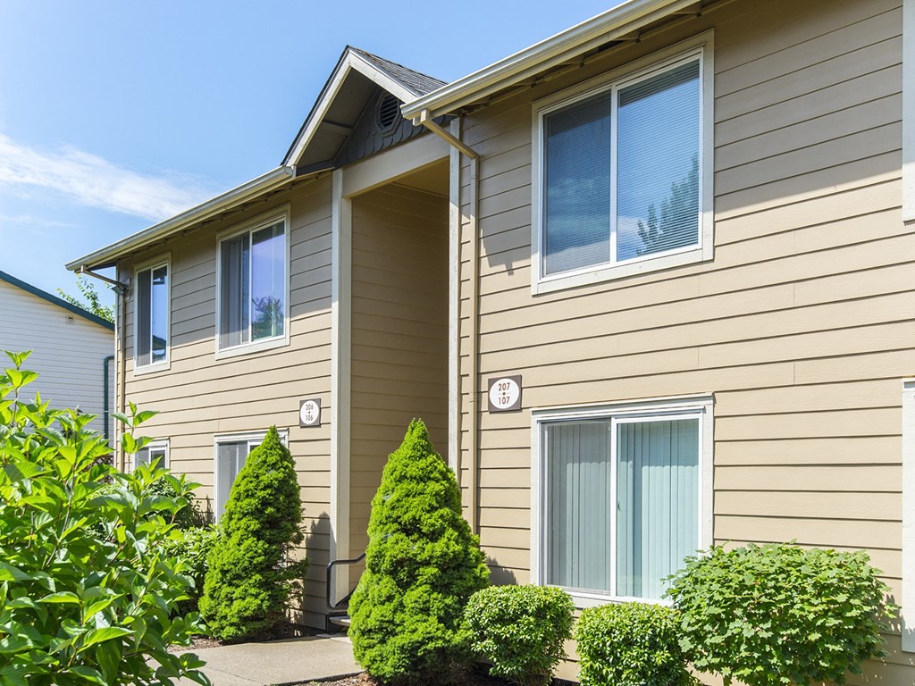 the exterior of a house with a sidewalk and shrubs