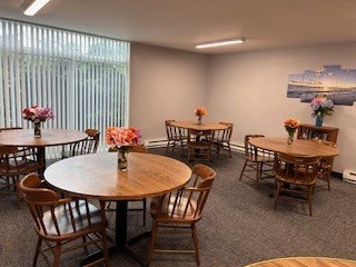 A room with round wooden tables and chairs, some with flowers on them.