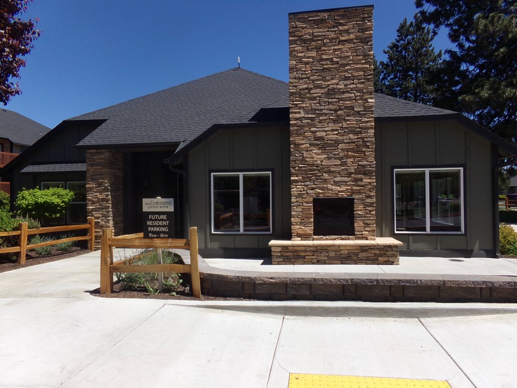 a black building with a stone chimney and a wooden fence