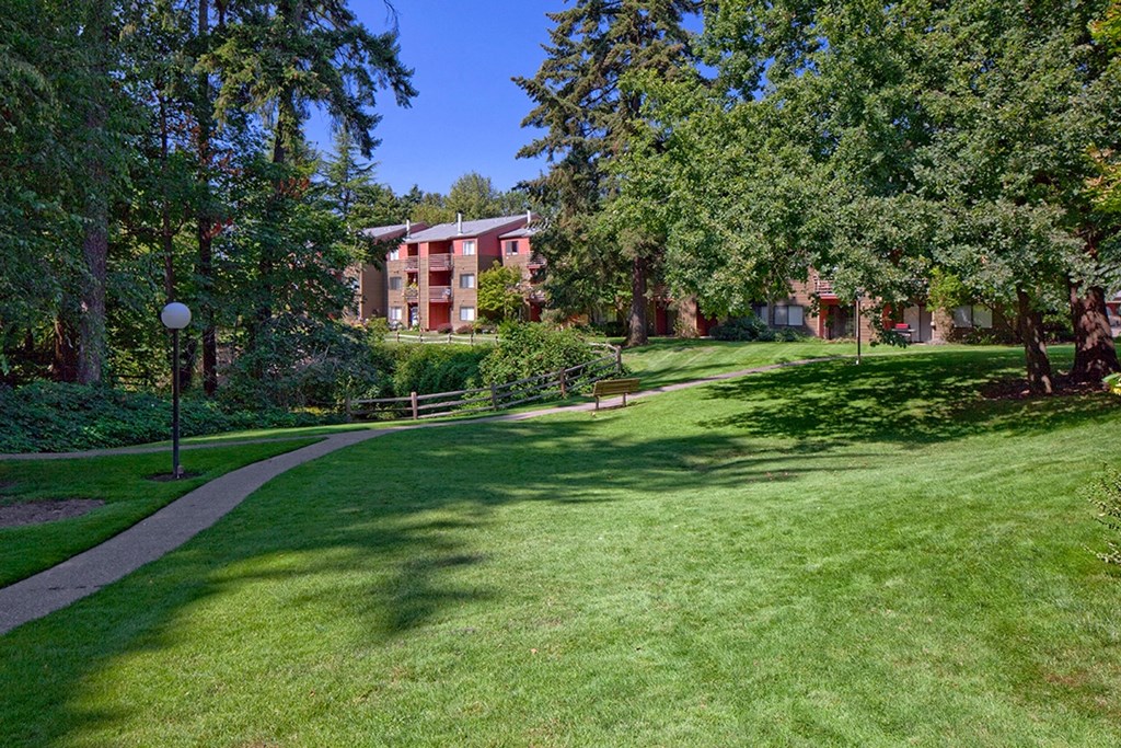 a grassy area with trees and buildings in the background