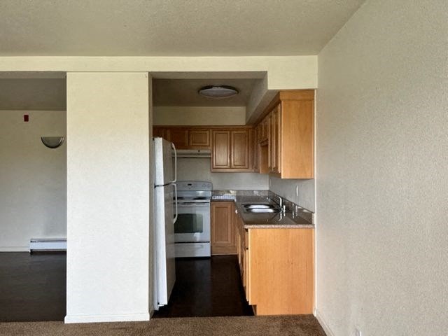 an empty kitchen with wooden cabinets and white appliances