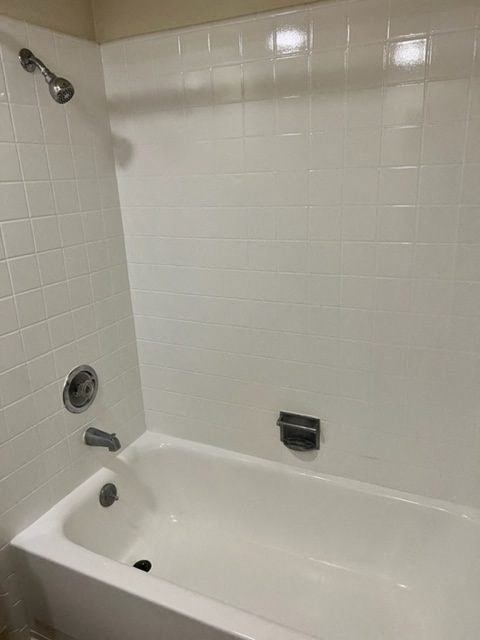 a white bath tub in a white tiled bathroom