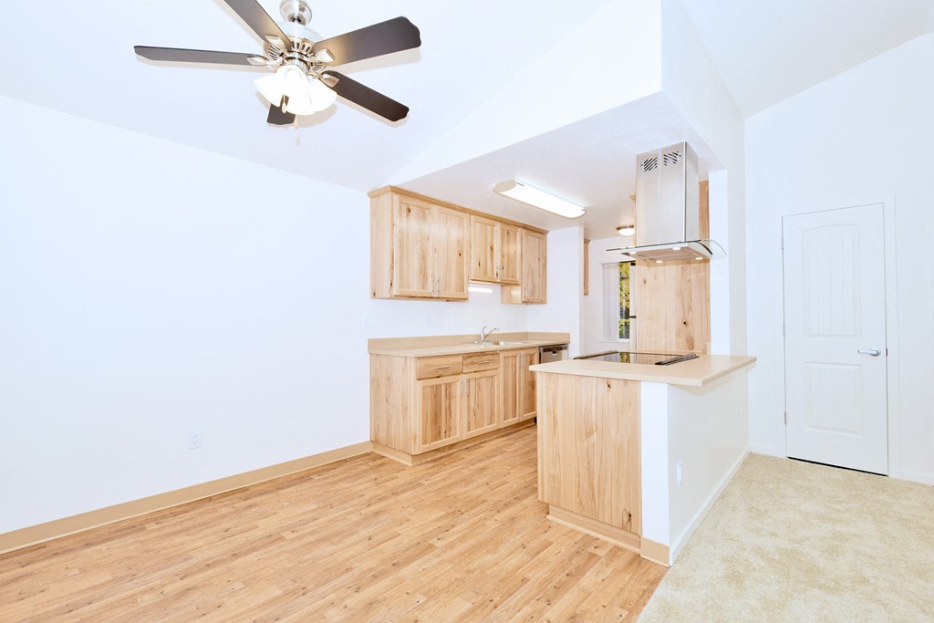 a living room with a kitchen and a ceiling fan