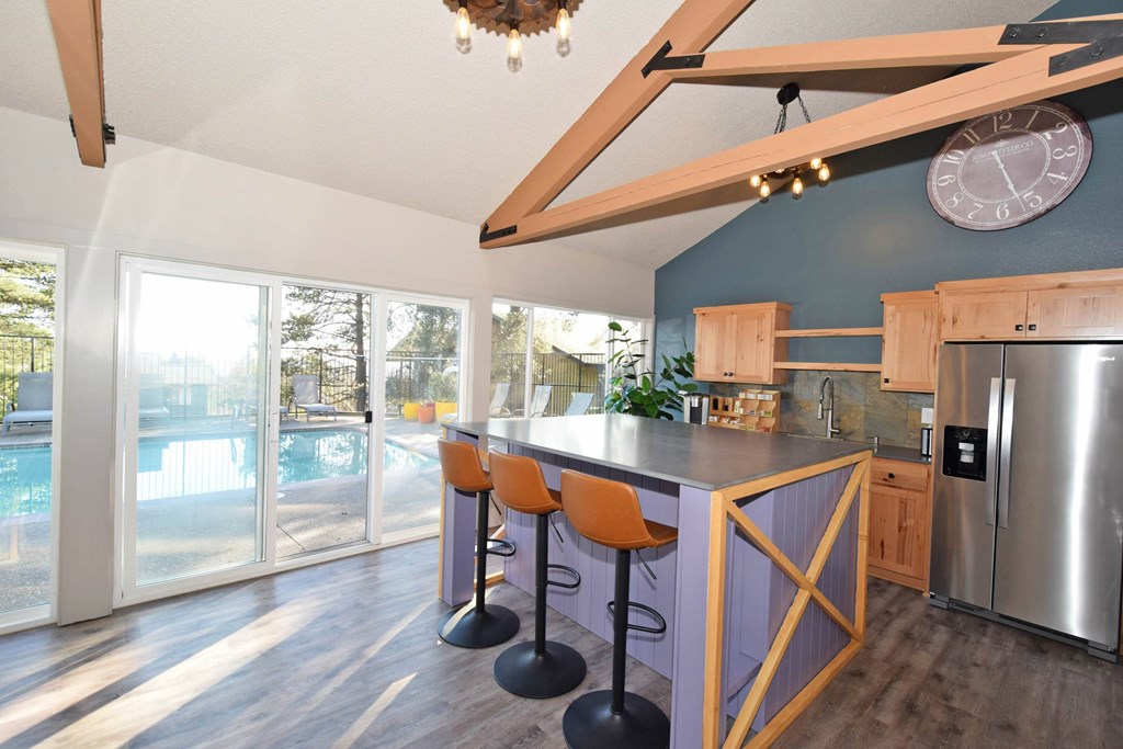 A kitchen with a purple wall and a bar area with stools.