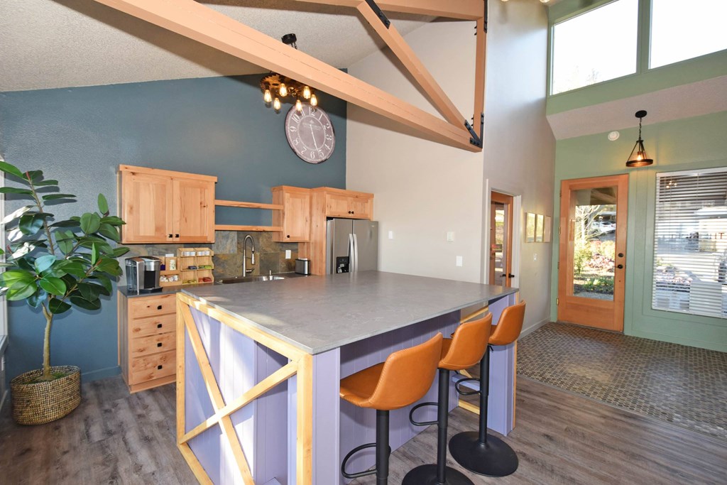 A kitchen with a purple island and orange chairs.