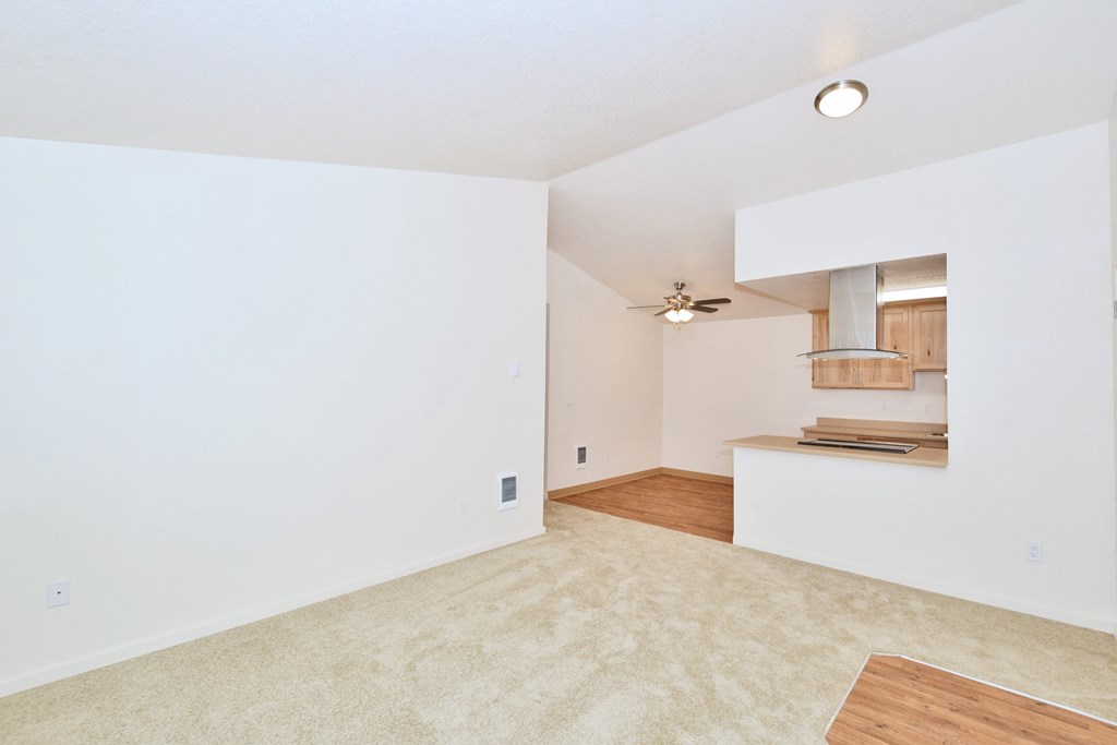 an empty living room and kitchen with a ceiling fan