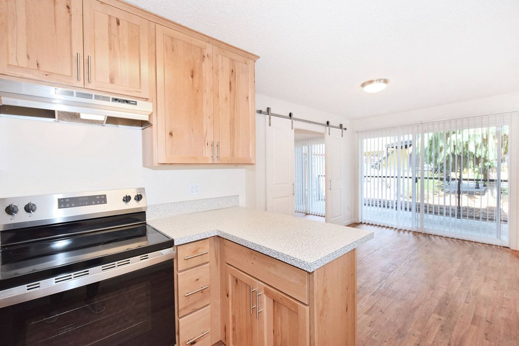a kitchen with wooden cabinets and a stove and a window