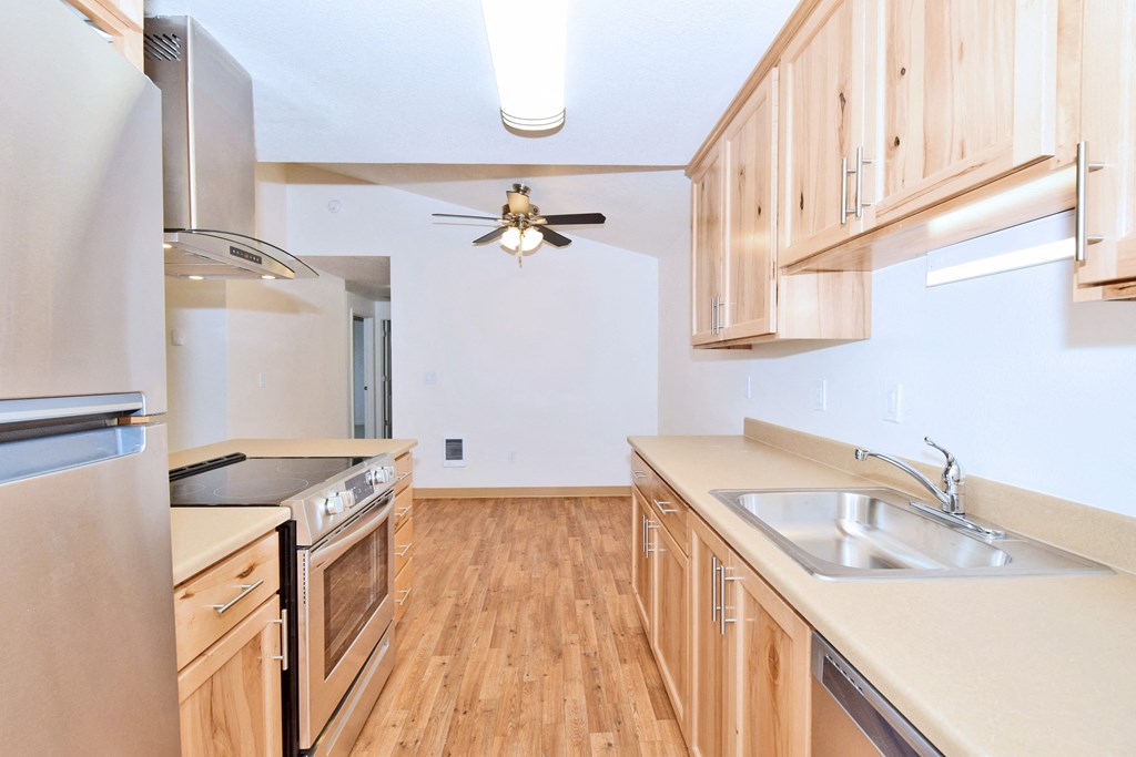 an empty kitchen with wood flooring and a ceiling fan