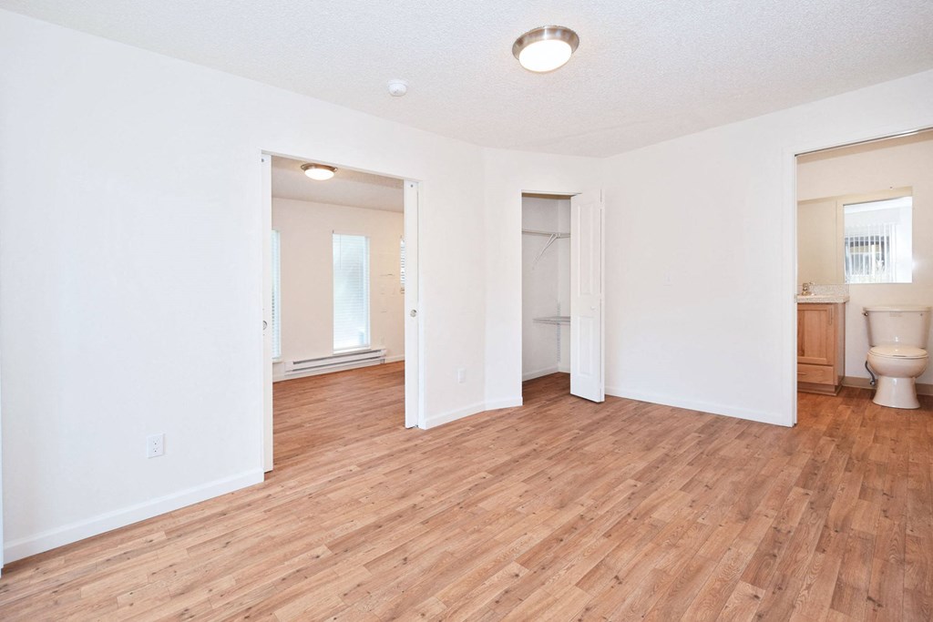 an empty living room with a wooden floor and a bathroom