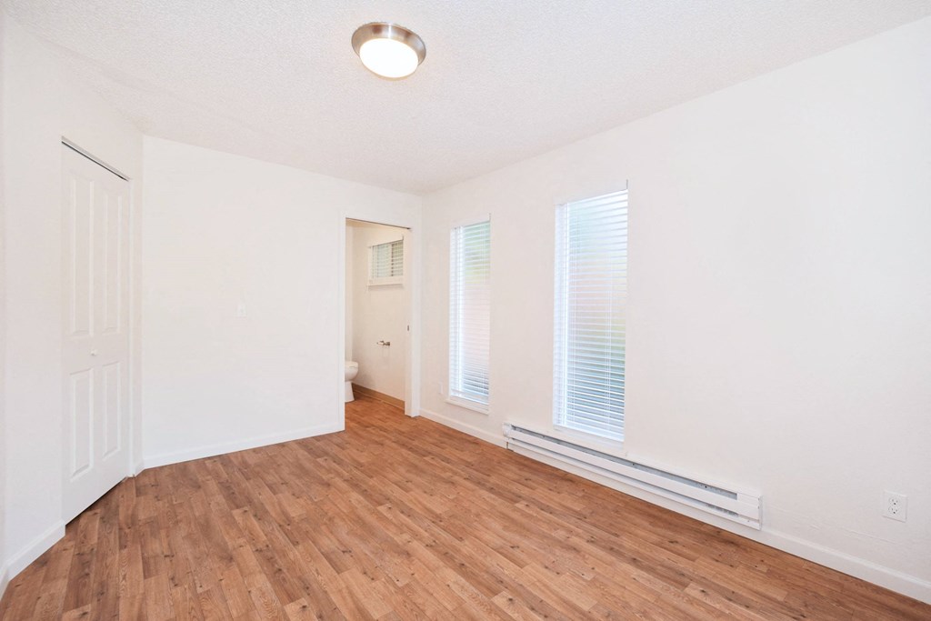 an empty living room with wood flooring and white walls